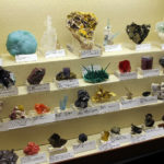 Mixed case of mineral specimens displayed on traditional fabric covered risers.